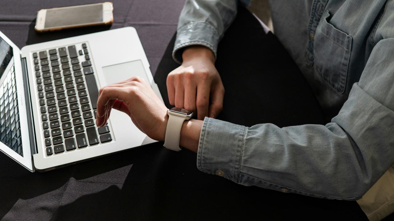 Orang dengan Jaket Denim Biru Menggunakan MacBook Pro